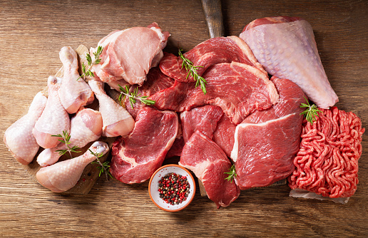 various types of fresh meat: pork, beef, turkey and chicken on a wooden table, top view